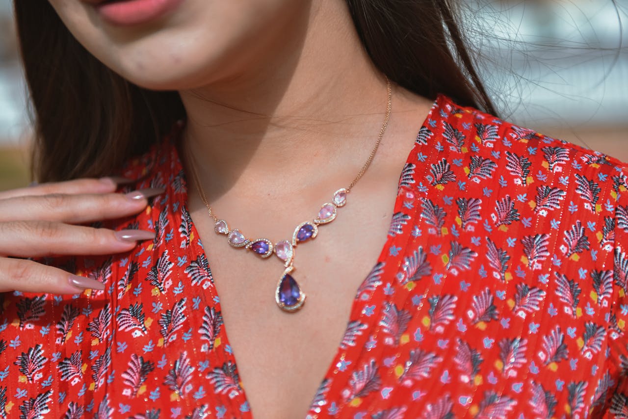 Close-up of a woman wearing a purple gemstone necklace against a floral dress.